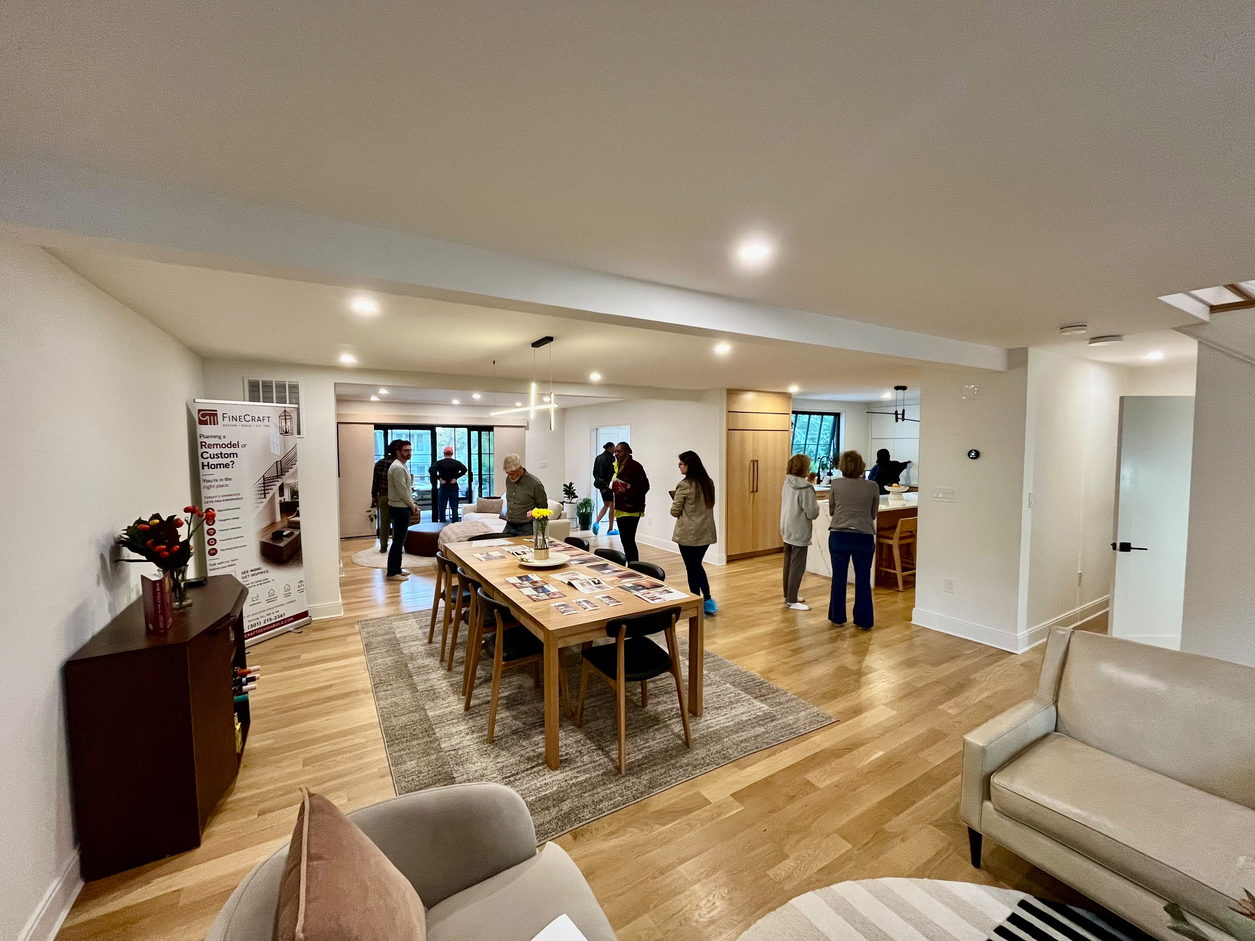 Guests exploring the connected living, dining, and kitchen spaces during the FineCraft home tour.