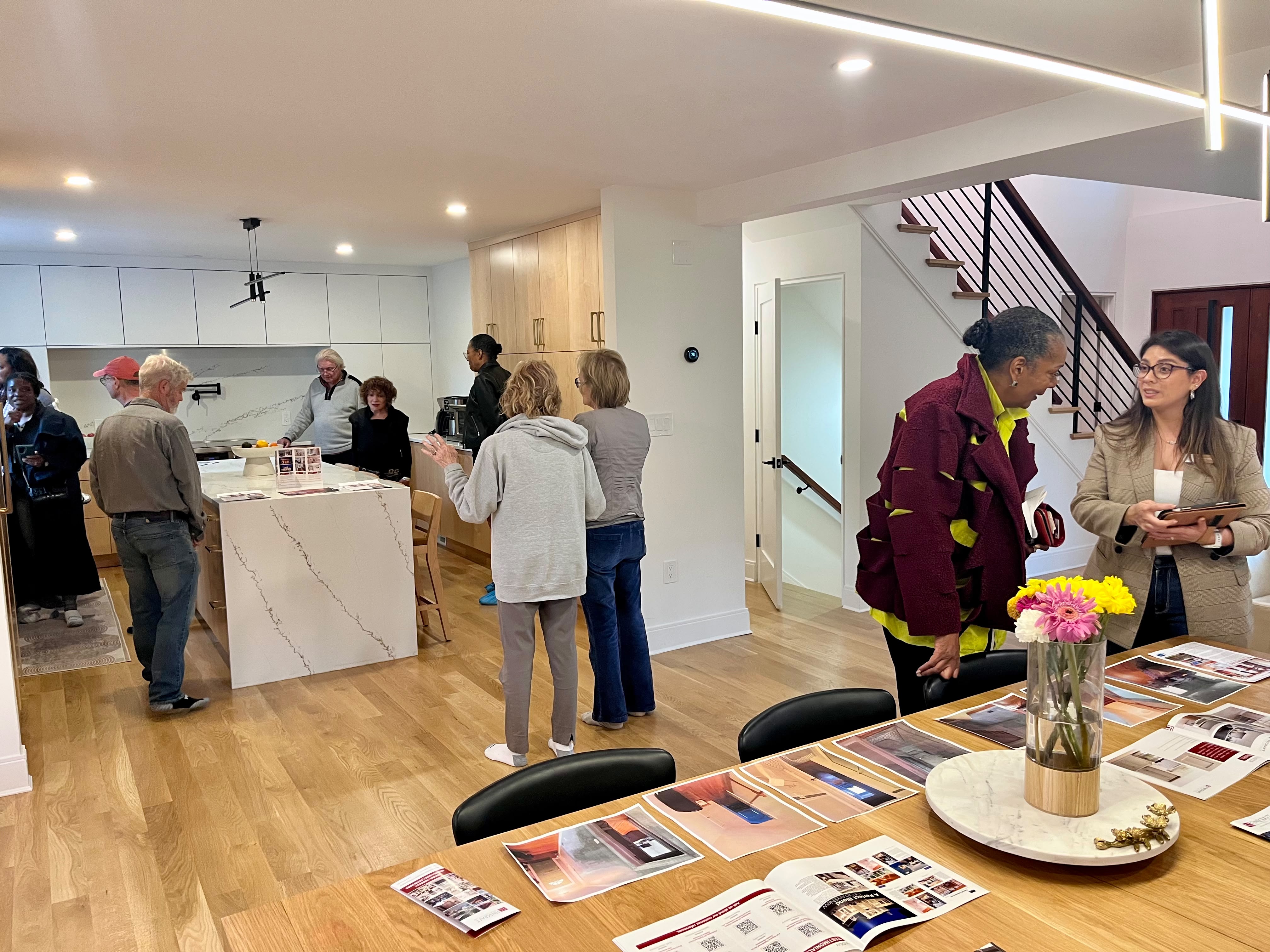 Tour guests chatting around the modern kitchen island and dining table.